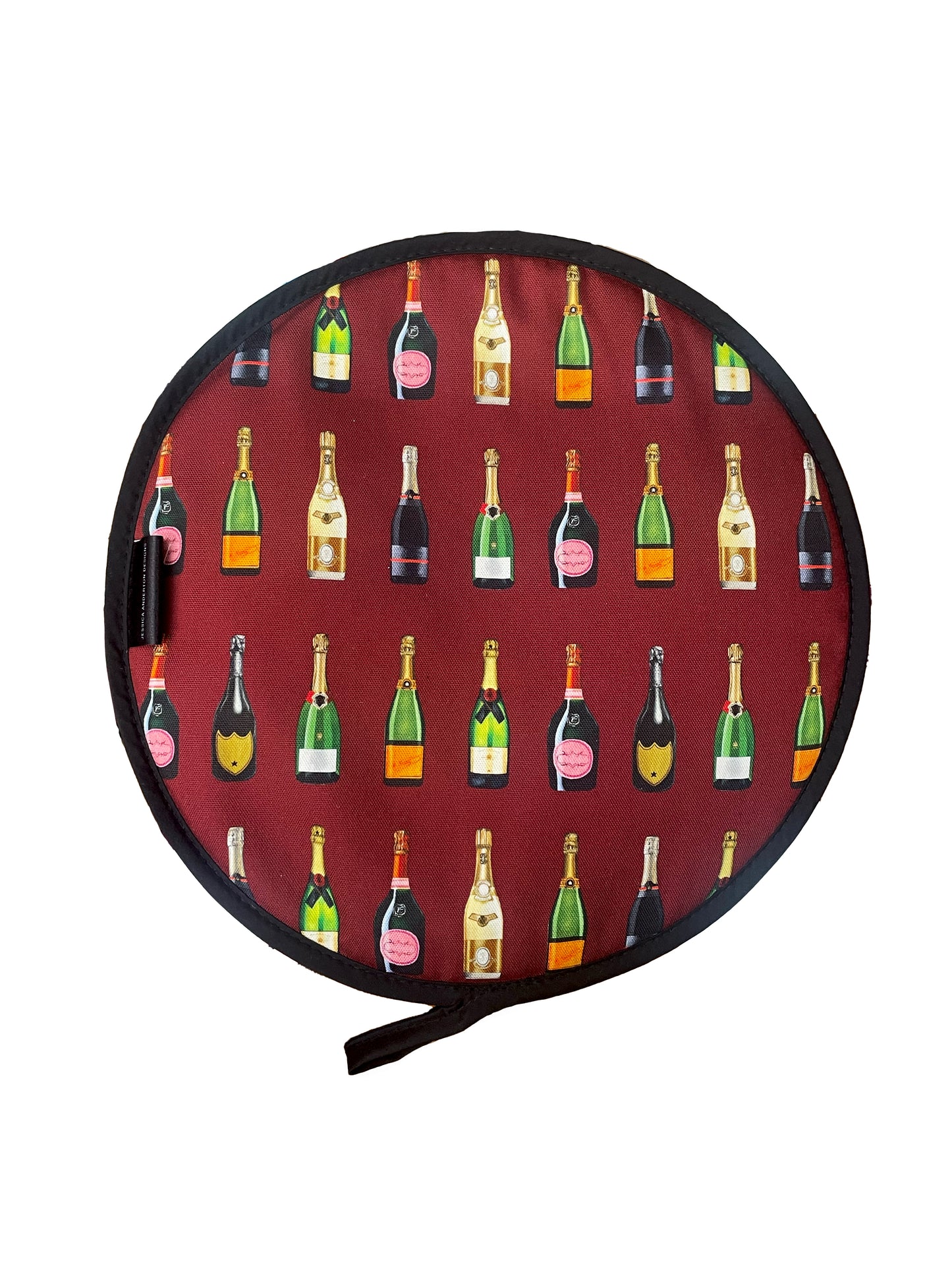 A round hob cover with a red background featuring a repeating pattern of champagne bottles in various colors.